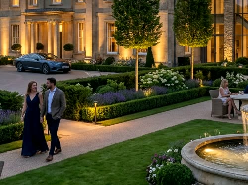 Couple strolling past illuminated estate fountains at dusk